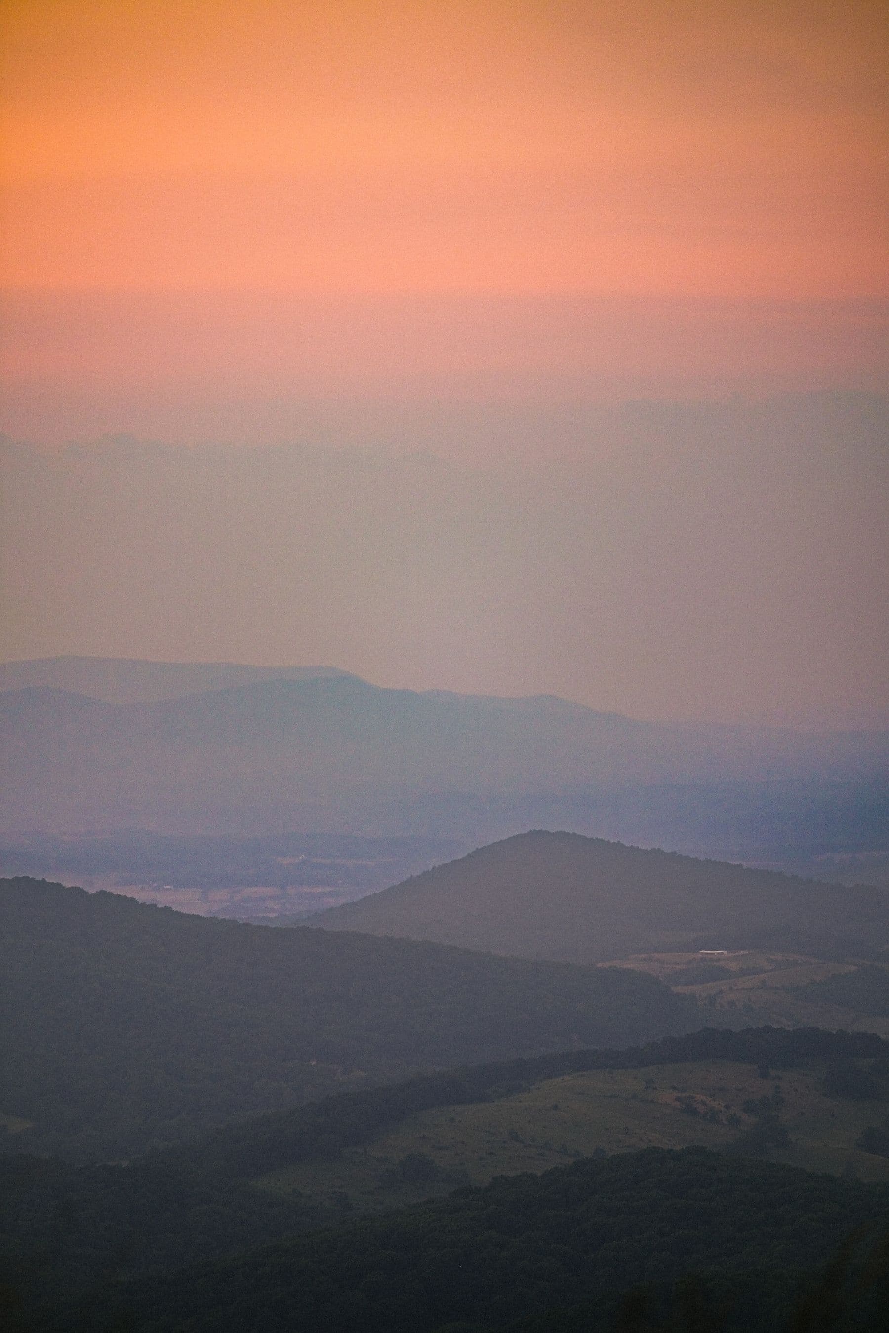 Layered Blue Ridge ridgelines fading into a warm sunrise haze over Virginia