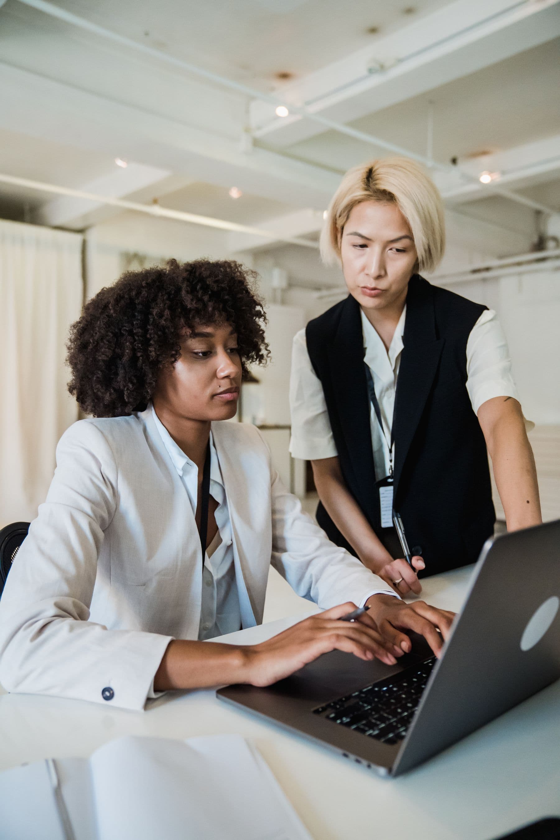 Two colleagues reviewing work together at a laptop in a bright office