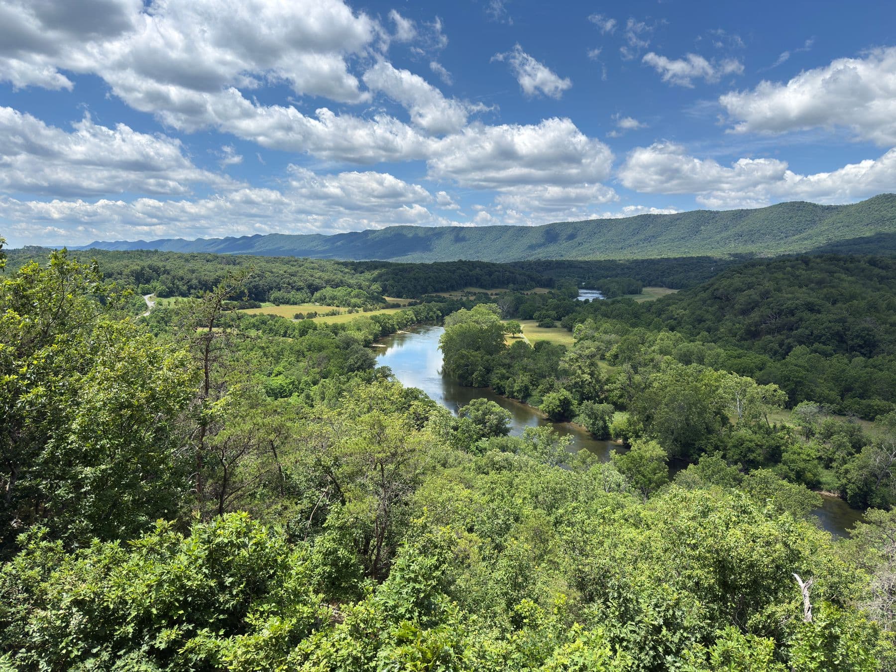 The Shenandoah River winding between wooded ridges under a summer sky