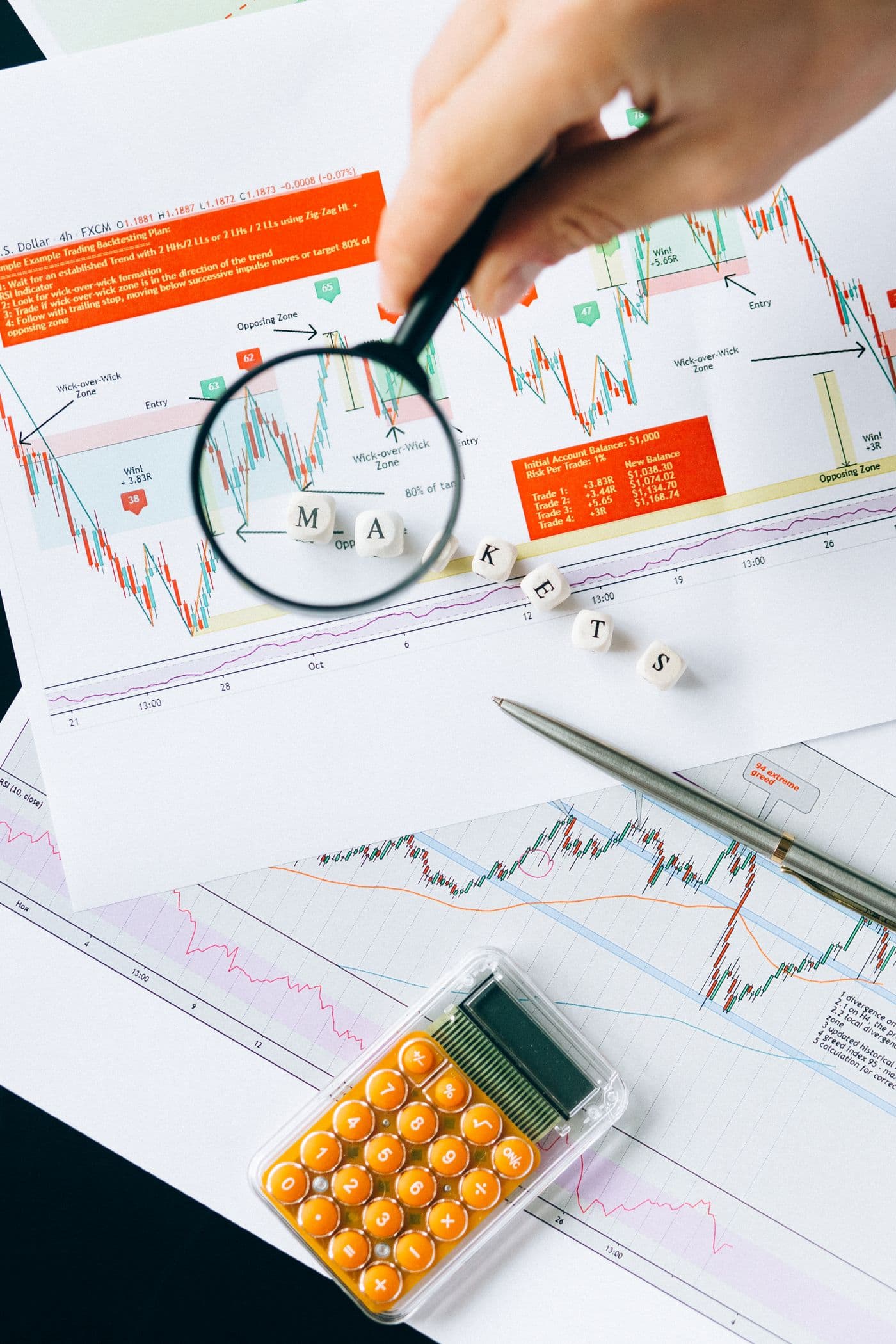 A magnifying glass over printed market data and charts
