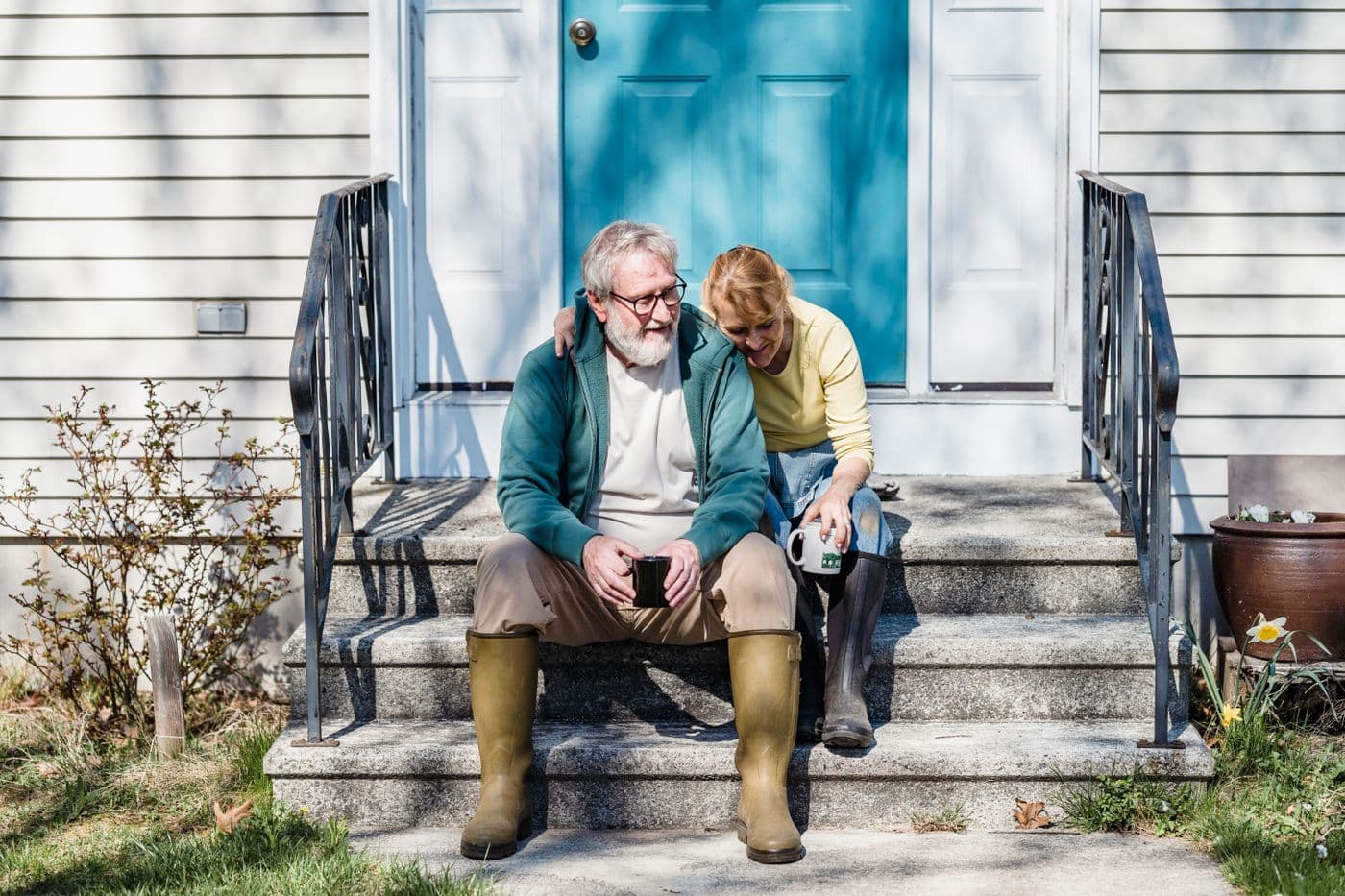 An older couple sitting together on their porch steps